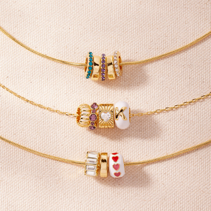 Three gold necklaces with decorative beads on a beige background