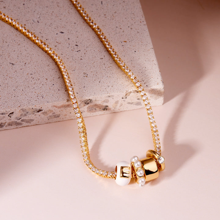 Gold necklace with pearl accents on a stone surface
