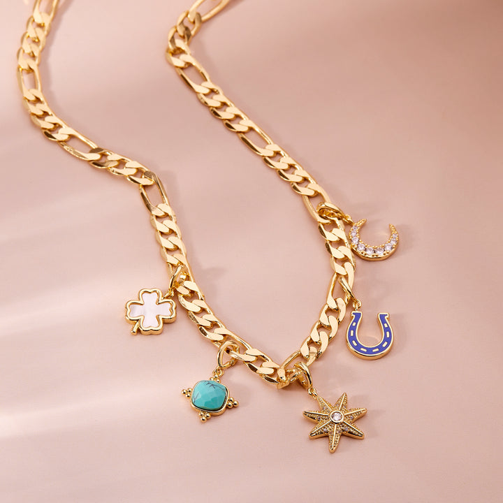 Gold chain necklace with various charms on a pink background