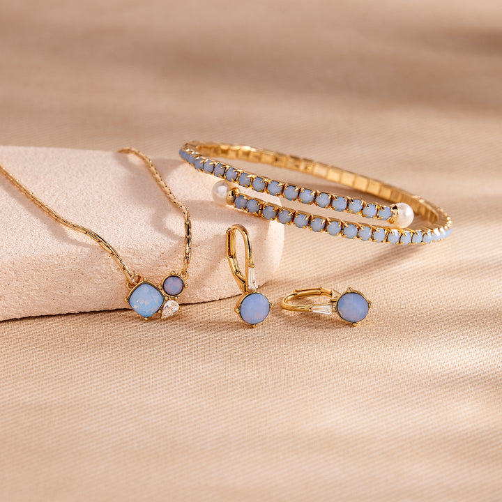 Gold jewelry set with blue stones on a beige fabric background