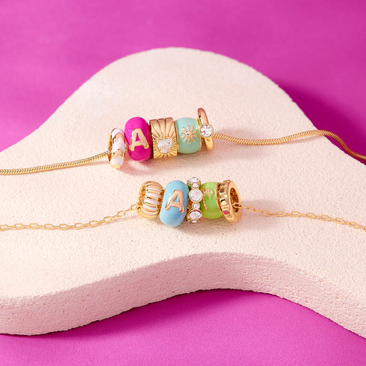 Jewelry set with colorful beads and gold chains on a white stand against a purple background