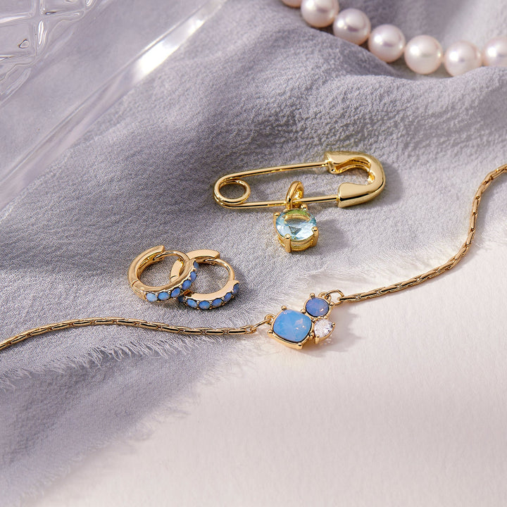 Gold jewelry with gemstones on a light gray fabric background