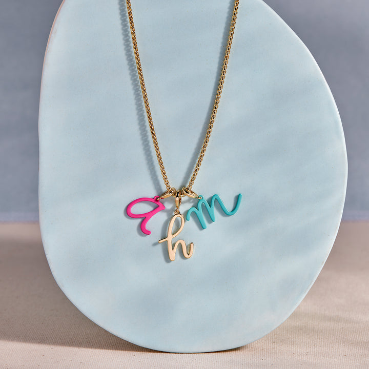 Necklace with colorful letter pendants on a light blue stand