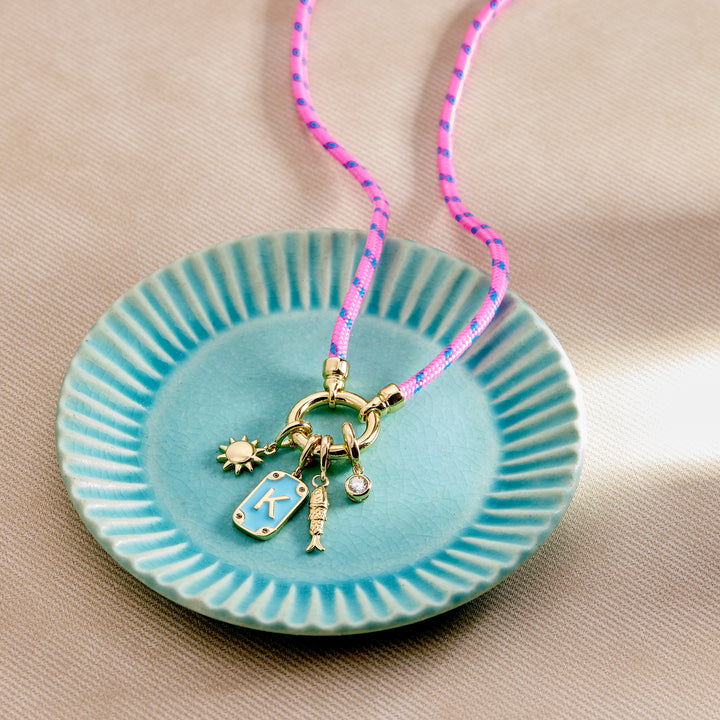 Necklace with charms on a turquoise dish against a beige background