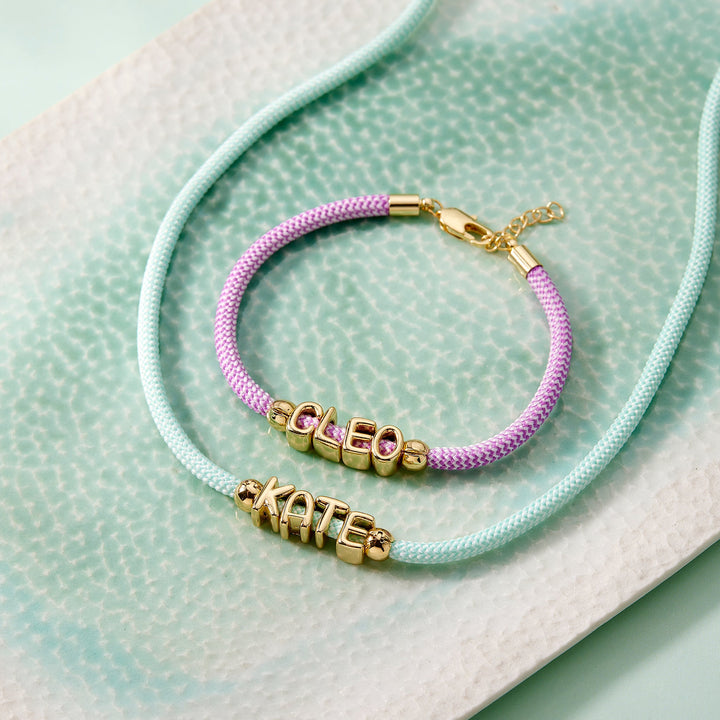 Purple bracelet with gold beads on a textured light green surface