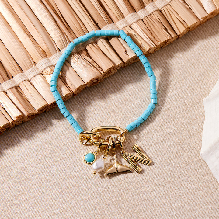 Bracelet with blue beads and gold charms on a textured surface