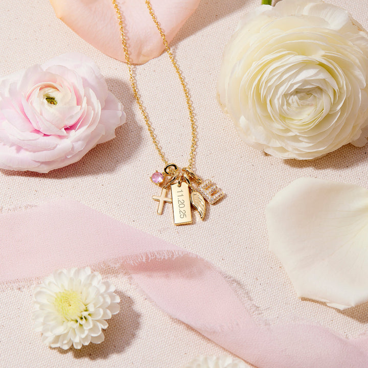 Gold necklace with a pendant on a pink surface with flowers
