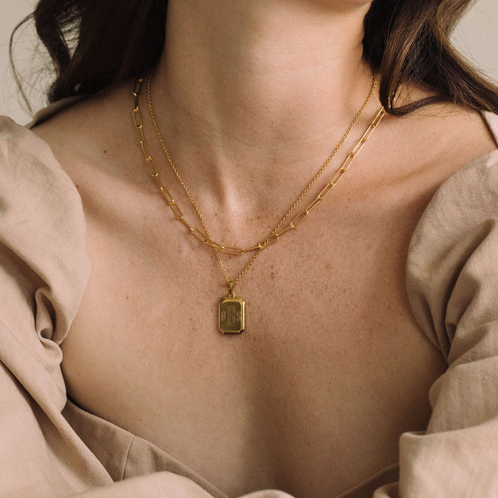 Woman wearing a beige blouse with puffed sleeves and gold jewelry against a neutral background