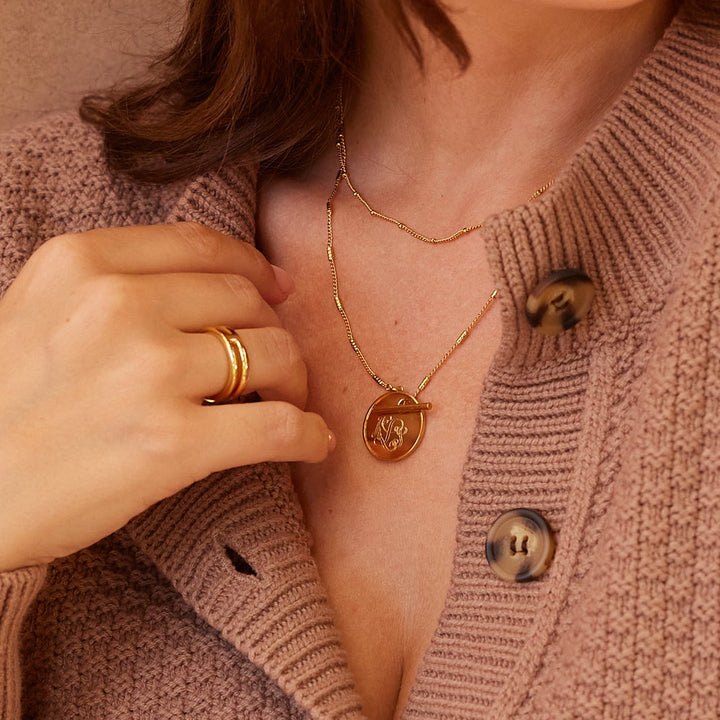 Woman wearing a brown knitted cardigan sitting indoors with a warm, neutral background.