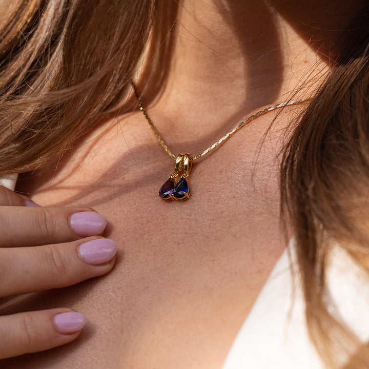 Close-up of a necklace with a pendant worn by a person with light skin and brown hair.