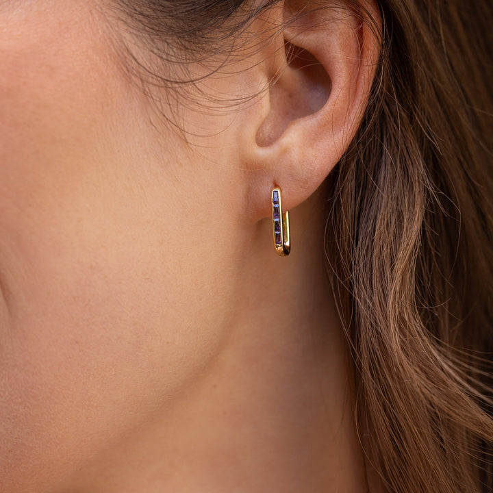 Close-up of an ear wearing a gold earring with embedded stones.