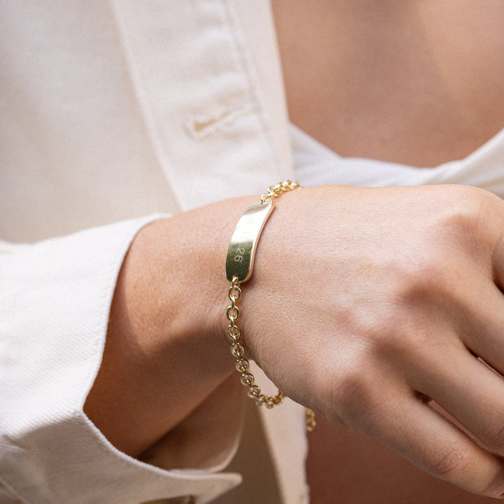 Close-up of a person wearing a gold bracelet on their wrist.