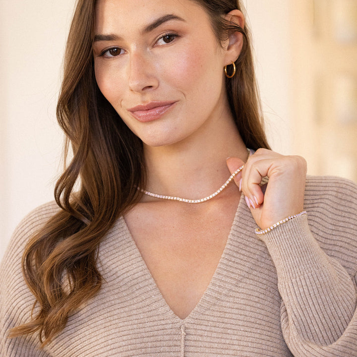 Woman wearing a pearl necklace and bracelet against a neutral background