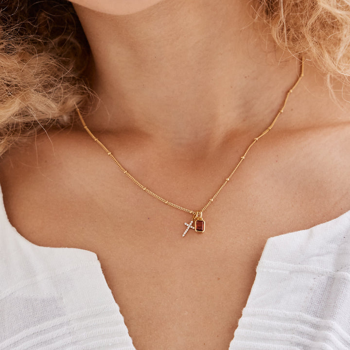 Woman wearing a white blouse with a necklace, close-up of her neck and shoulders.
