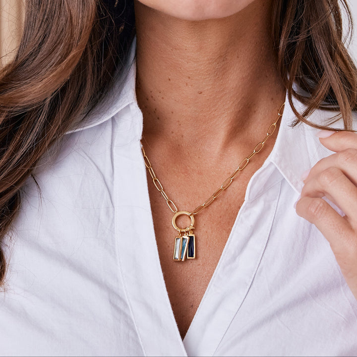 Woman wearing a white shirt with jewelry against a neutral background