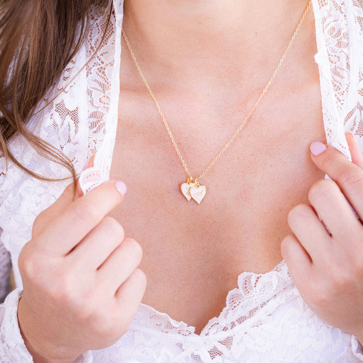 Close-up of a person wearing a gold necklace with heart-shaped pendants.