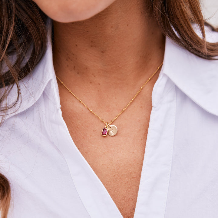 Close-up of a person wearing a gold necklace with a pendant.