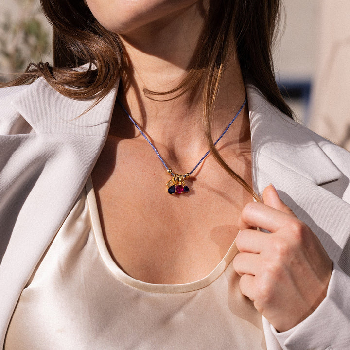 Woman wearing a white blazer and top with a necklace, standing outdoors.