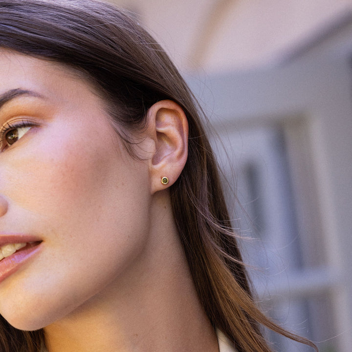 Close-up of a woman wearing a green gemstone earring with a blurred background