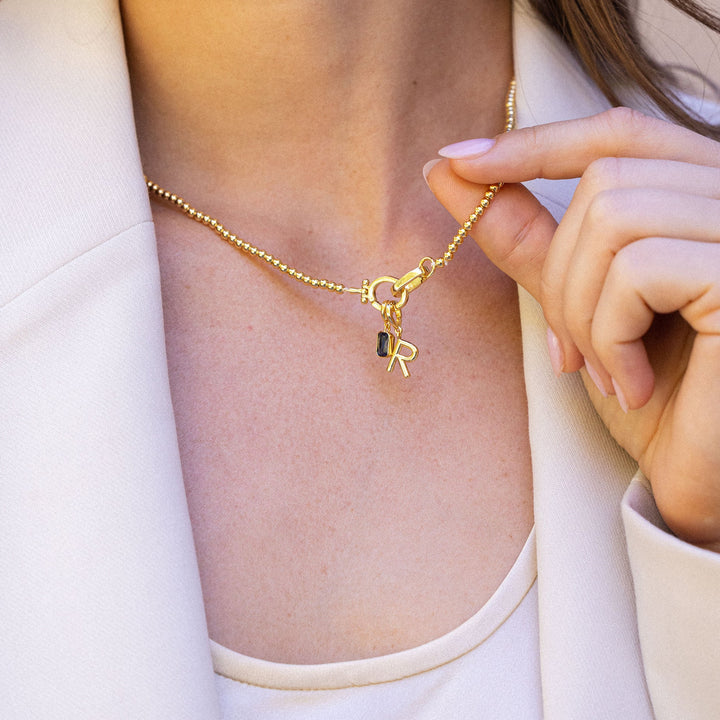Woman wearing a gold necklace with a key pendant, close-up on neck and blazer.