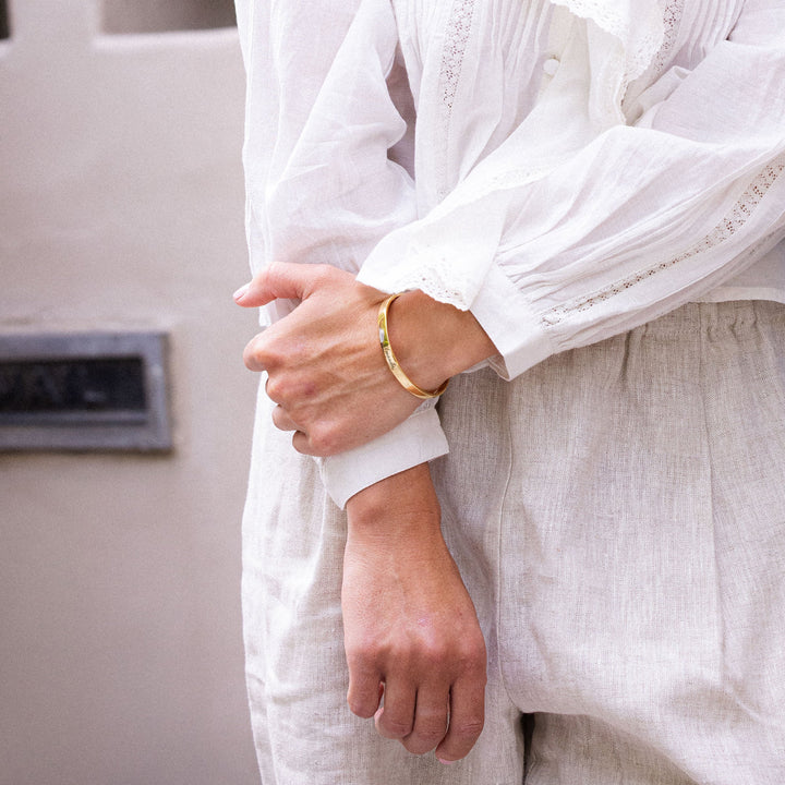 Woman in a white outfit laughing against a neutral wall.