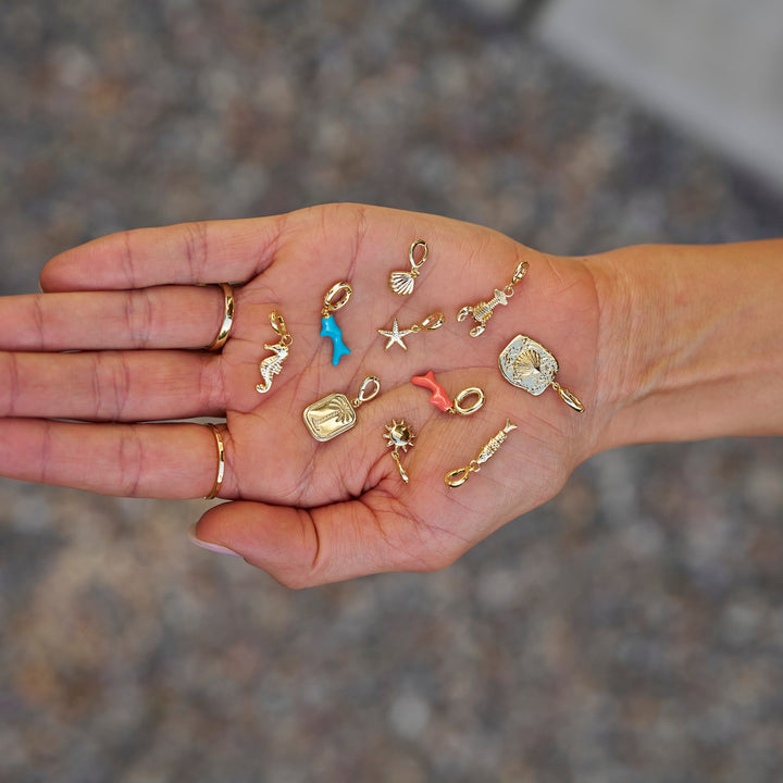 Hand holding various small jewelry pieces against a blurred background