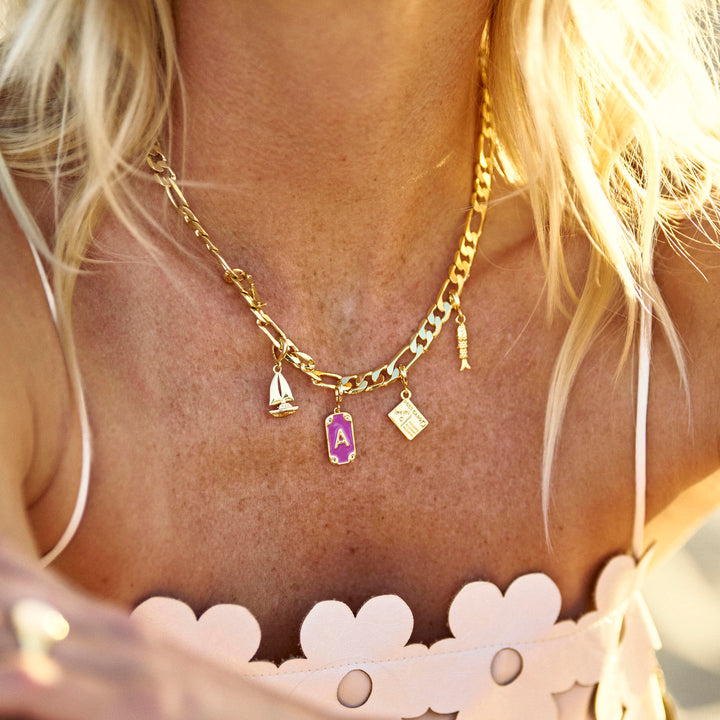 Close-up of a person wearing a gold necklace with charms, blurred background