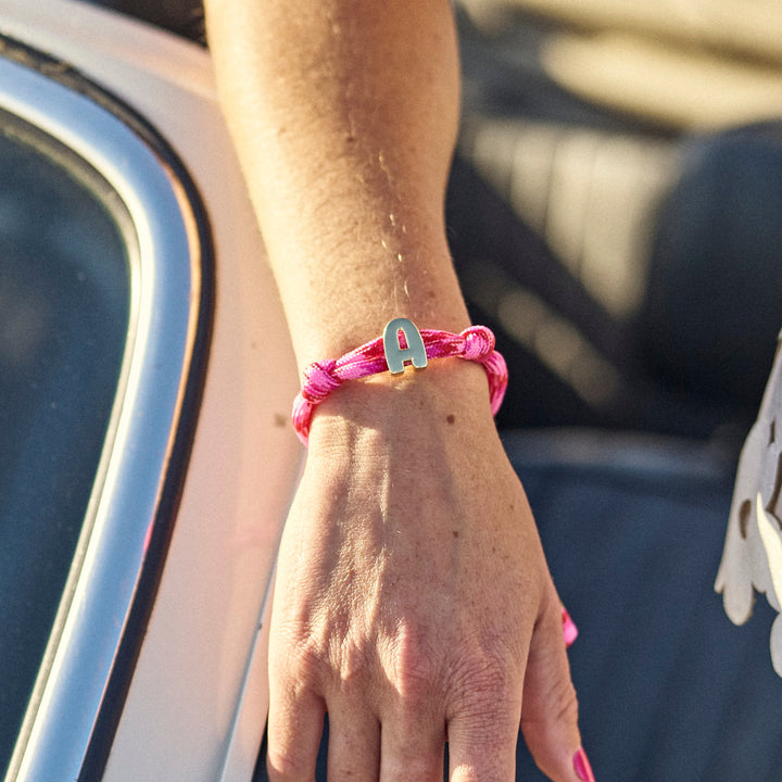 Person wearing a pink bracelet by a car window